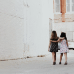 Two young girls walking together toward a city of bright white buildings, symbolizing partnership, trust, and accountability in organizational culture.