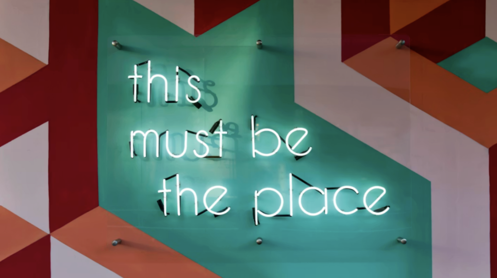 Neon sign reading “This must be the place,” symbolizing finding the right place to volunteer and building a welcoming nonprofit volunteer community.