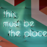 Neon sign reading “This must be the place,” symbolizing finding the right place to volunteer and building a welcoming nonprofit volunteer community.
