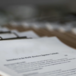 Stack of documents on a clipboard representing structured agendas, motions, and procedures used to run nonprofit board meetings effectively.