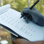 Person checking off a volunteer schedule while volunteers work in the background, illustrating tools and systems for organizing nonprofit volunteer programs.