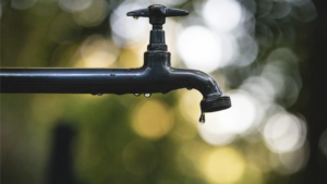 An outdoor faucet slowly dripping water, symbolizing wasted time from inefficient workflows.