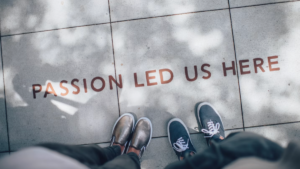 Team members standing on a sidewalk with the words "passion led us here" painted at their feet