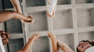 Upward view of team members' hands clasped together in celebration