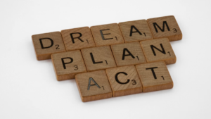 Scrabble tiles arranged to spell the words dream, plan, and act